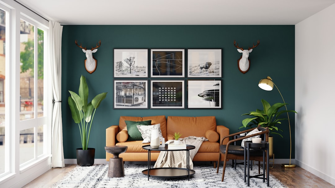 Modern living room with sage green accent wall, tan leather sofa, and gallery wall showcasing 2026 interior color trends