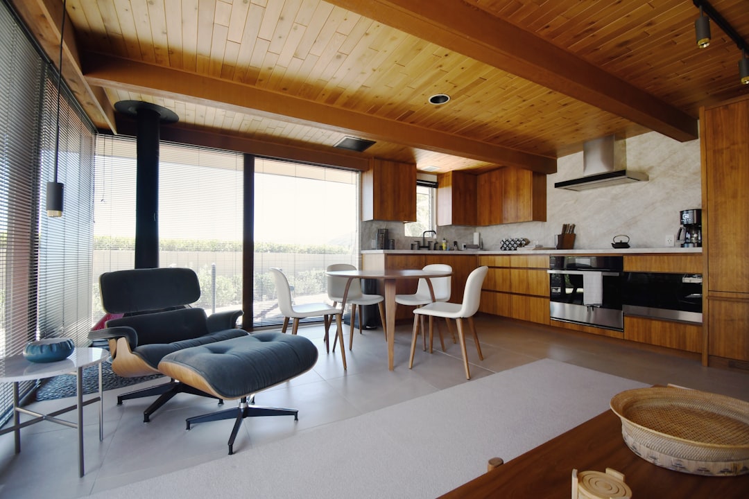 Mid-century modern living space featuring Eames lounge chair, wooden credenza, and open-plan kitchen with natural materials. Photo by Ian Schneider